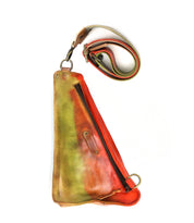 The Adept by Bed Stu is a triangular-shaped sling bag crafted from sustainable leather, featuring multi-colored hues of vibrant red, green, and brown. It includes a zipper and an adjustable strap.
