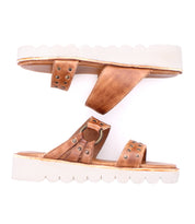 Bed Stu's Chow sandals feature brown leather with stud details and chunky rubber soles, showcased on a mirrored white background.