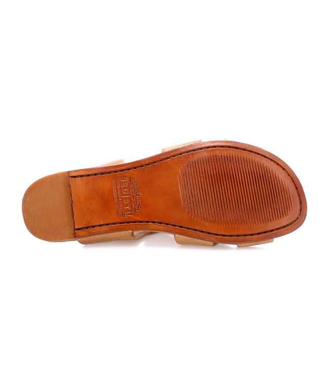 A close-up view of the bottom sole of a Configure slip-on leather sandal by Bed Stu featuring a combination of smooth and textured brown leather with the brand name "BED|STU" stamped near the center. The sandal boasts a cushioned inner sole for added comfort.