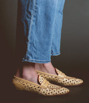 Person wearing blue jeans and tan loafers handcrafted in Italy with a playful cutout pattern called Cornflower by Bed Stu.