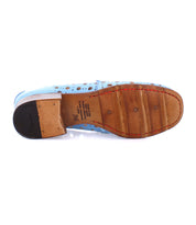 Bottom view of a light blue perforated penny loafer, Cornflower by Bed Stu, with a playful circular cutout pattern, featuring a brown leather sole and black heel patch.