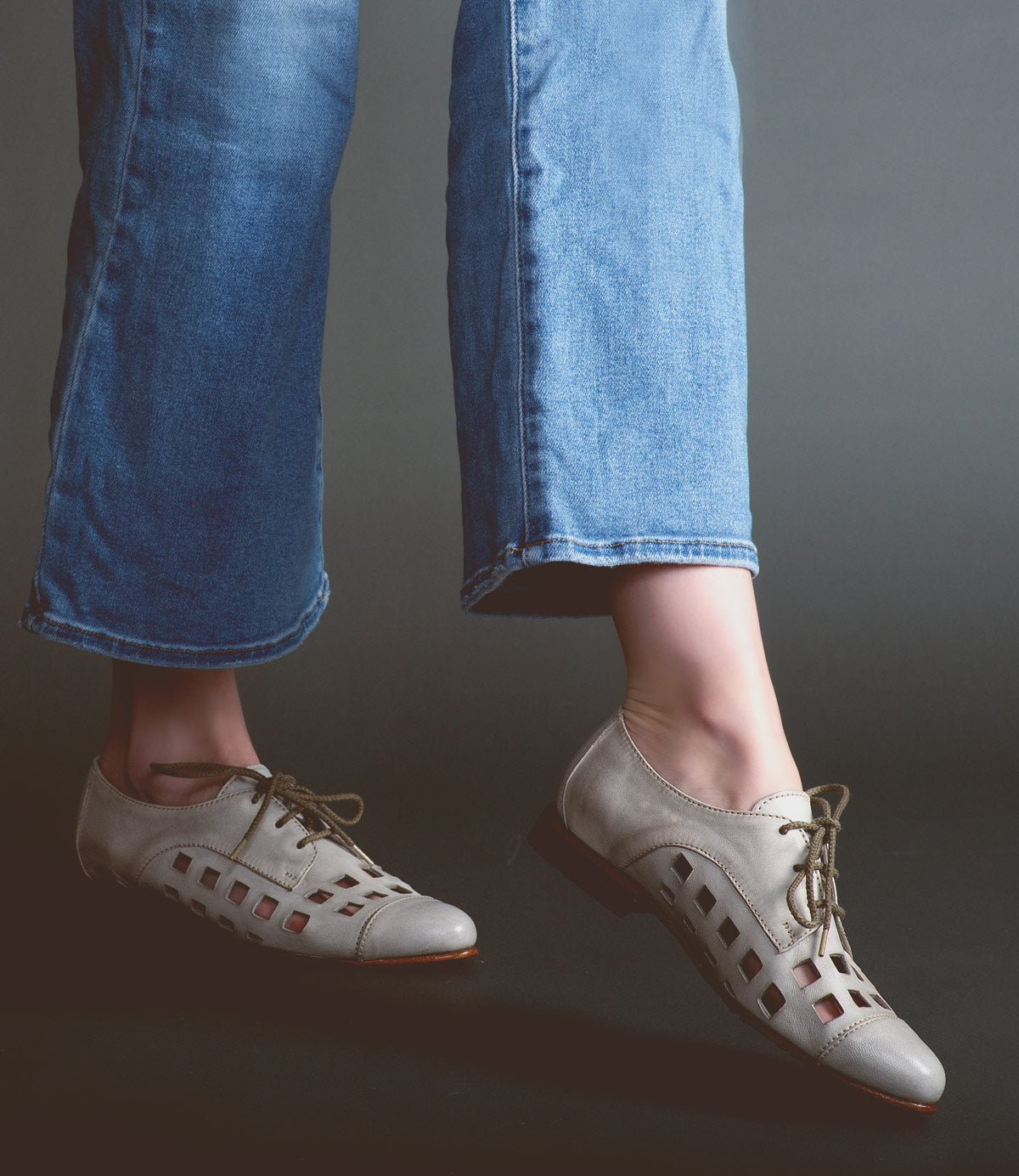 Person wearing blue jeans and grey handcrafted Decoy shoes by Bed Stu against a grey background.