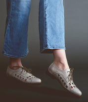 Person wearing blue jeans and grey handcrafted Decoy shoes by Bed Stu against a grey background.