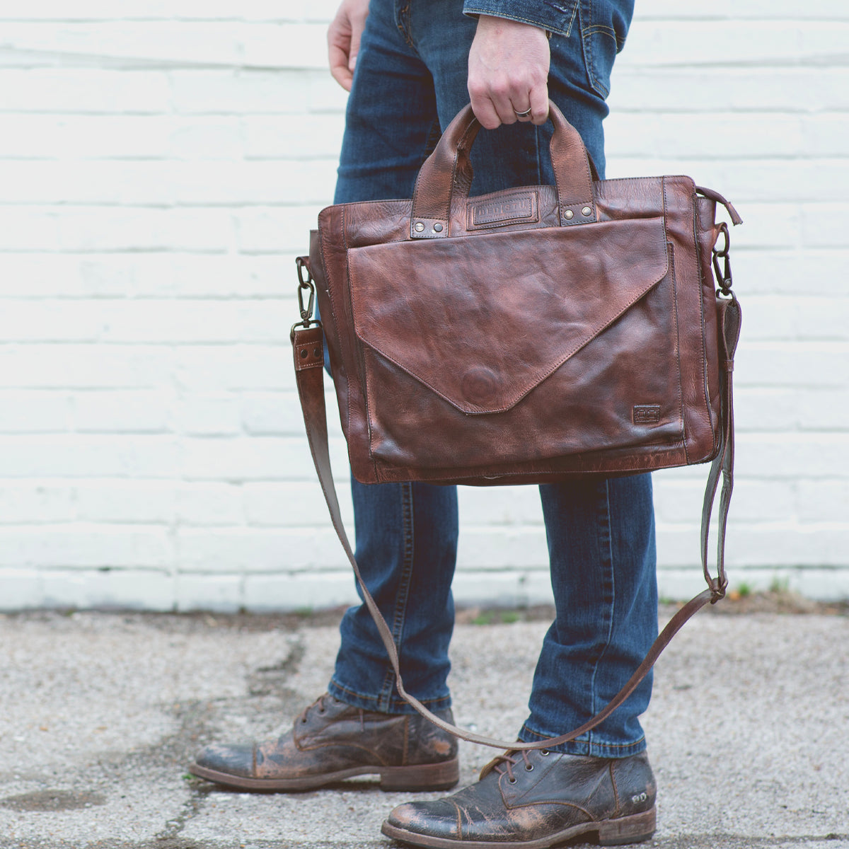 A man holding a Depp brown leather briefcase symbolizing organization by Bed Stu.
