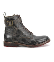 The Bed Stu Endure is a single worn black lace-up ankle boot featuring a decorative buckle on the side and a red rubber outsole, displayed in profile against a white background.