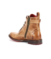 The Bed Stu Endure is a tan lace-up ankle boot with a side zipper, red leather lining, and brown sole, exuding rugged sophistication in this back-left view.