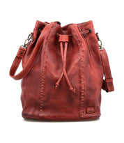 The Bed Stu Eve is a red leather bucket bag with a drawstring cinch, visible side stitching, and a shoulder strap that can also be worn crossbody.