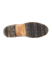The image shows the bottom view of the Bed Stu Fierce Men’s derby shoe, featuring a worn textured rubber sole and branded leather midsole that combine classic style with a modern twist.