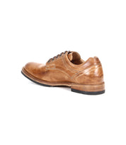 The Bed Stu Fierce is a men’s brown leather derby shoe with visible stitching, black sole, and laces. This classic design with a modern edge is shown from a back-side angle on a white background.