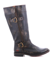 The Bed Stu Gogo Lug is a tall, black moto-style leather boot featuring two decorative buckles, a side zipper, distressed finish, low heel, and sturdy lug outsole.