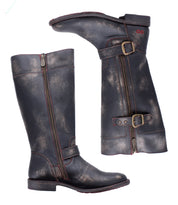 The Bed Stu Gogo Lug boots are tall, distressed black moto-style leather with dual zippers and buckles, shown side by side—one standing upright and one laying on its lug outsole.