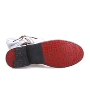 The image shows the underside of the Bed Stu Gogo Lug shoe, featuring a white upper and a red and black textured rubber lug outsole with geometric patterns and distinctive markings.