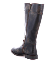 The Bed Stu Gogo Lug is a tall black moto-style leather boot with a visible side zipper and low heel, shown against a white background.