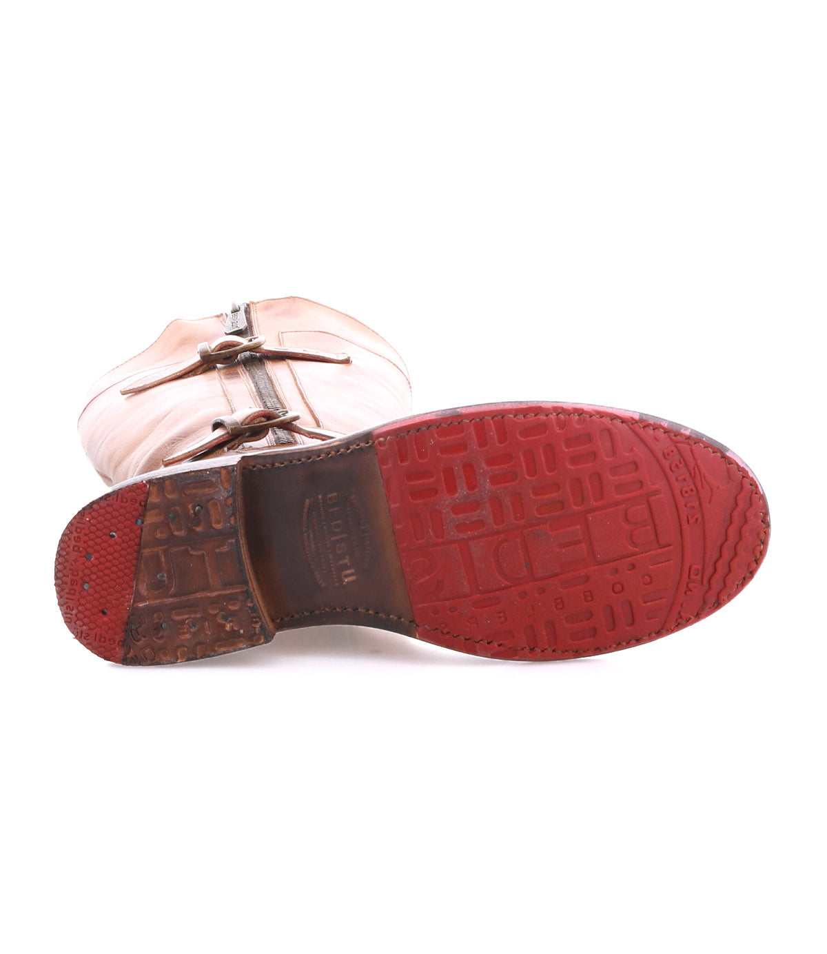 A single Bed Stu Gogo Lug moto-style tan leather boot is shown on its side with the red lug outsole facing up, showcasing its tread pattern and logo.