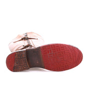 A single Bed Stu Gogo Lug moto-style tan leather boot is shown on its side with the red lug outsole facing up, showcasing its tread pattern and logo.