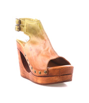 The Imelda by Bed Stu is a tan leather wedge sandal with an open toe, wooden platform sole, metal studs, and double ankle buckles for a stylish finish.