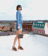 A woman in a denim shirt standing on top of a building wearing open-toe leather heels called Jinkie by Bed Stu.