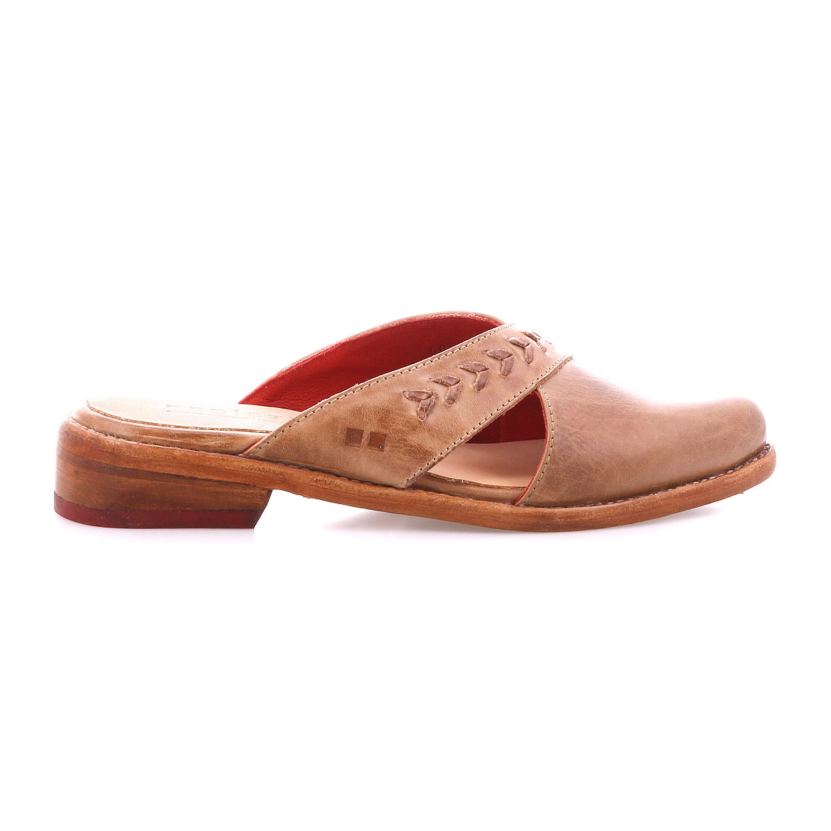 The Bed Stu Jockey is a brown leather slip-on mule with a sleek design, low wooden heel, decorative stitching on the upper strap, and red interior lining, shown in profile against a white background.