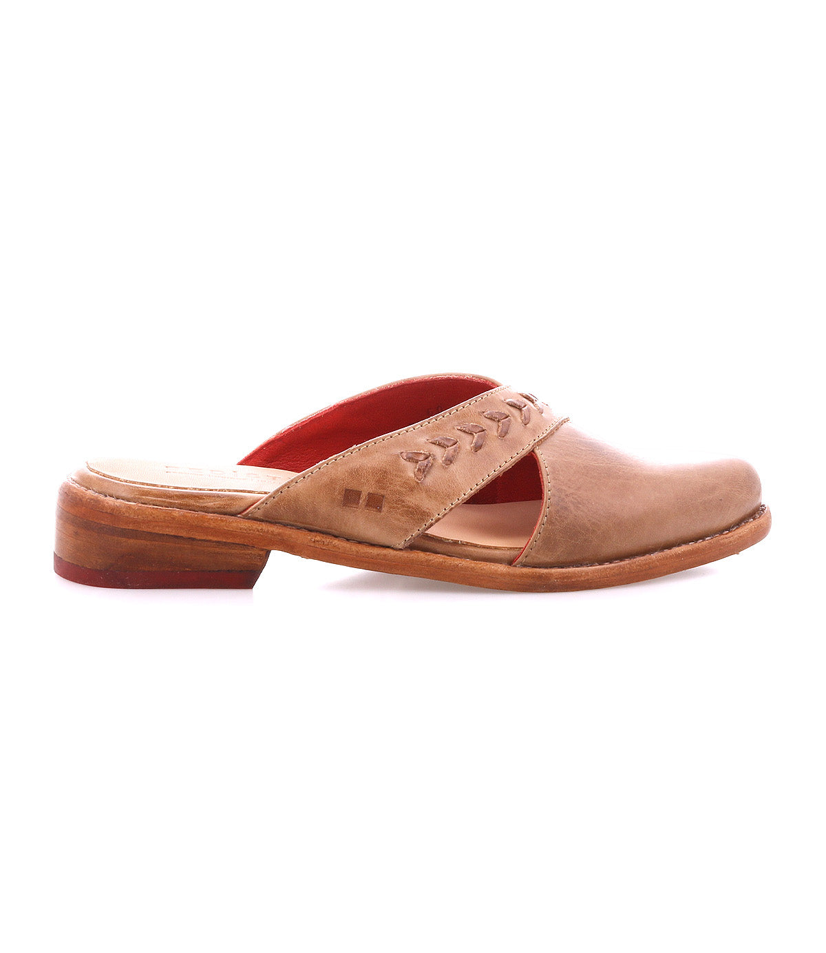 The Bed Stu Jockey is a brown leather slip-on mule with a sleek design, low wooden heel, decorative stitching on the upper strap, and red interior lining, shown in profile against a white background.