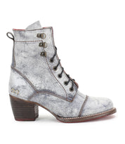 A lone, gray Bed Stu Judgement boot showcases a lace-up design and a distressed texture, highlighted by metallic accents and set on a chic block heel against a white backdrop.