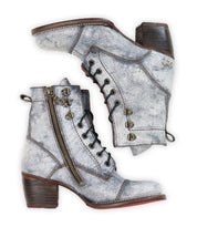 The Bed Stu Judgement boots, crafted from distressed silver leather, feature a lace-up design, zippers, and block heels arranged side by side.