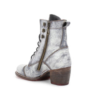 Introducing the Bed Stu Judgement boot: a silver-gray textured ankle boot with a side zipper, lace-up design, and a stylish block heel. Seen from a side and slightly rear angle, it perfectly embodies both elegance and edge.