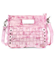The Keiki by Bed Stu is a pink leather handbag with a textured finish, cutout handle, and woven panels. Adorned with studs, it features an adjustable shoulder strap for crossbody wear and a zip-top closure for security.