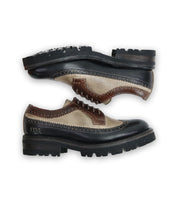 A pair of black, brown, and beige leather Lita K III shoes with rugged soles arranged horizontally on a white background exude a retro chic vibe. Crafted by Bed Stu.