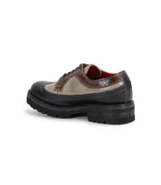 A brown and beige leather Lita K III with a black sole, by Bed Stu, featuring brogue detailing and laces, displayed at an angle, exudes retro chic vibes.
