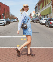 Woman in a Bed Stu Lita K III sustainable fashion denim dress and striped shirt walking across a street in an urban setting.