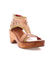 The Bed Stu Locket is a tan leather sandal with laser-cut floral details, an ankle strap, and a wooden wedge heel in a handcrafted style, shown on a white background.