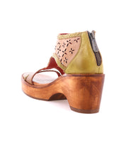 The Bed Stu Locket is a vintage-inspired sandal with green and beige leather, laser-cut floral details, artisanal craftsmanship, an ankle zipper, and an open toe.