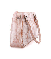The Rockababy by Bed Stu is a textured beige handbag with brown accents, two handles, metal details, and a stitched design. It comes with a crossbody strap for added versatility.