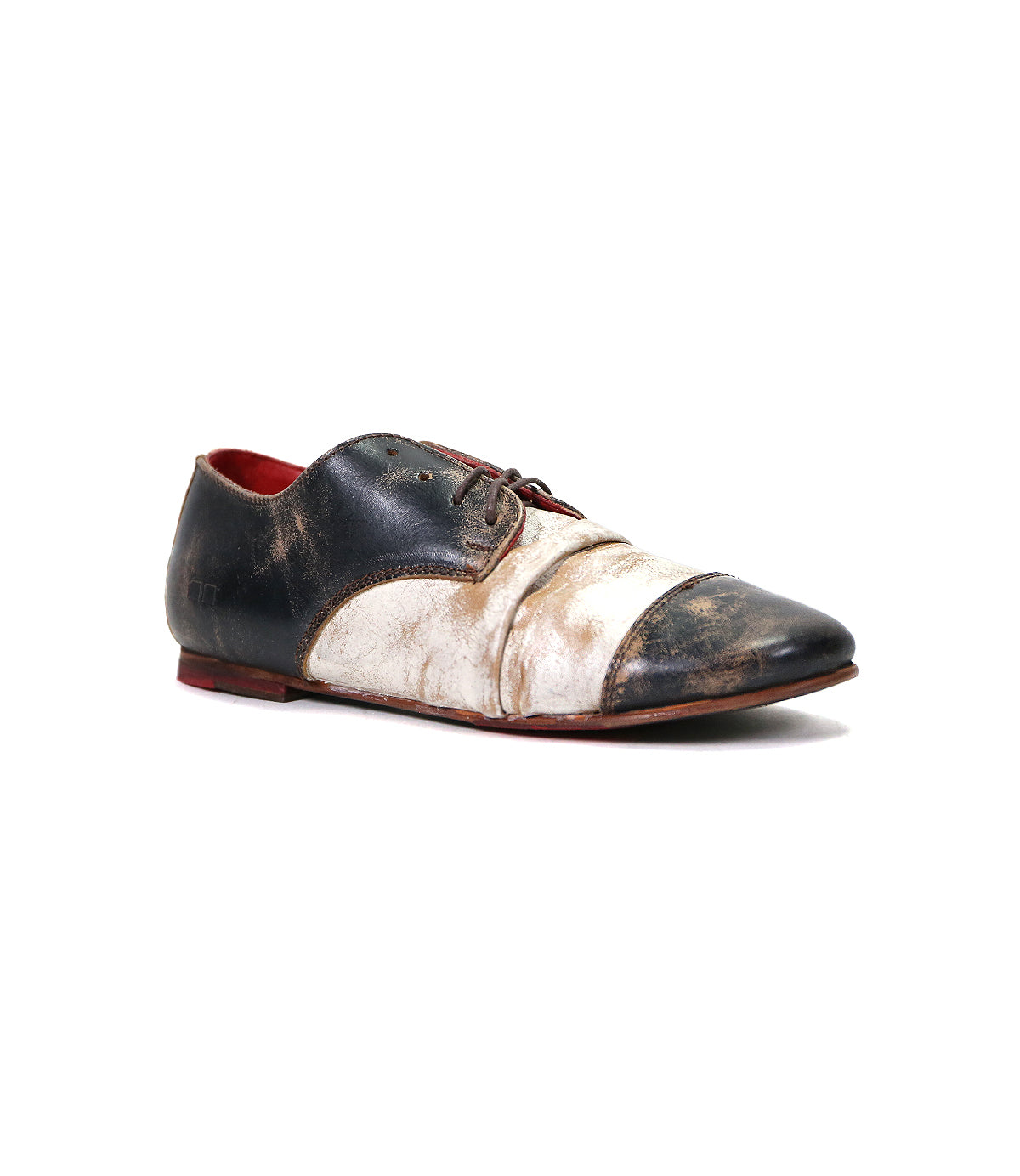 A worn-out Bed Stu Rumba II wingtip black and white men's dress shoe isolated on a white background.