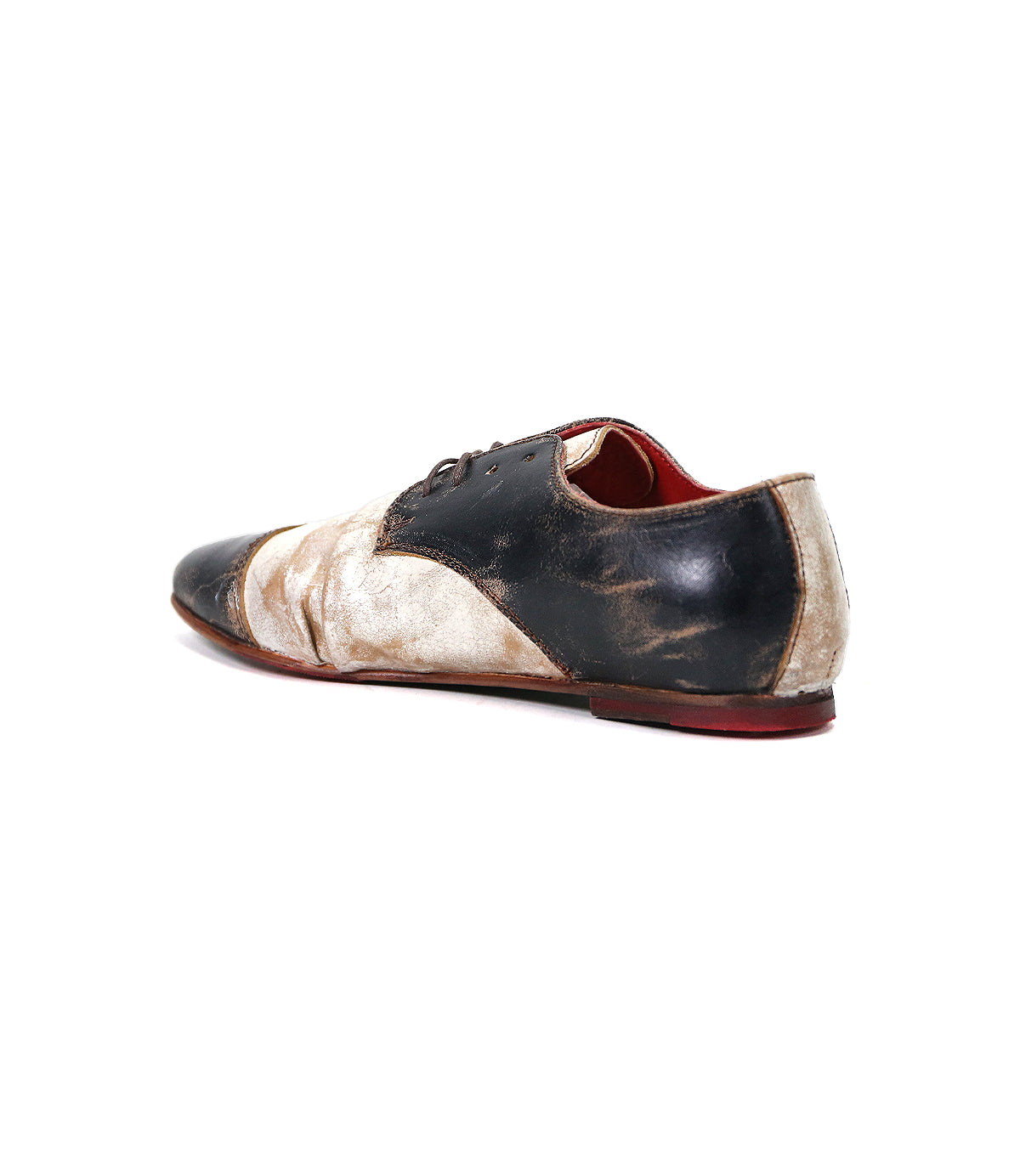 A single worn-out, two-toned leather wingtip shoe with black laces and a red sole, isolated against a white background by Bed Stu Rumba II.