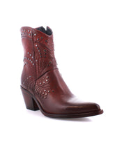 Introducing the Sposa by Bed Stu: an ankle bootie crafted from brown vegetable-tanned leather, adorned with decorative stitching and metal studs. It also features a block heel and a convenient side zipper.