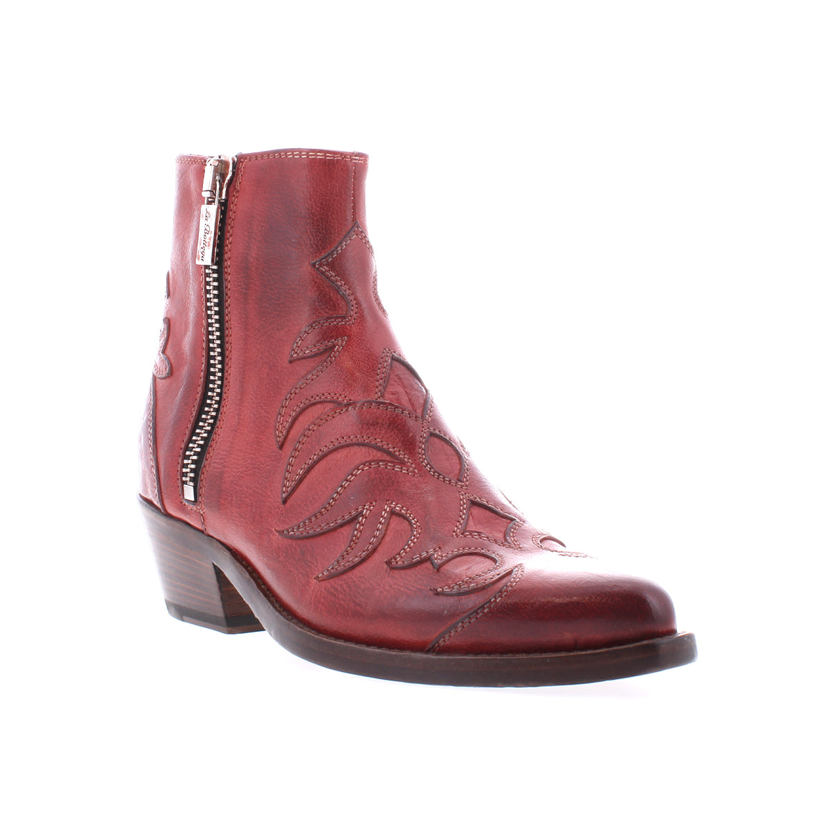 The Bed Stu Tentativa is a red leather ankle boot featuring artisan details, decorative stitching, a side zipper, low block heel, and a slightly pointed toe.