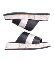 The Bed Stu Vext sandals are black and white platform slides featuring wide horizontal stripes and unique colors, with visible wear marks on the leather-wrapped sole and sides.