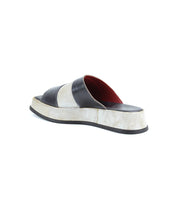 The Bed Stu Vext is a black and white platform slide sandal featuring a thick strap, leather-wrapped sole, and bold red interior for striking color blocking visible from the back.