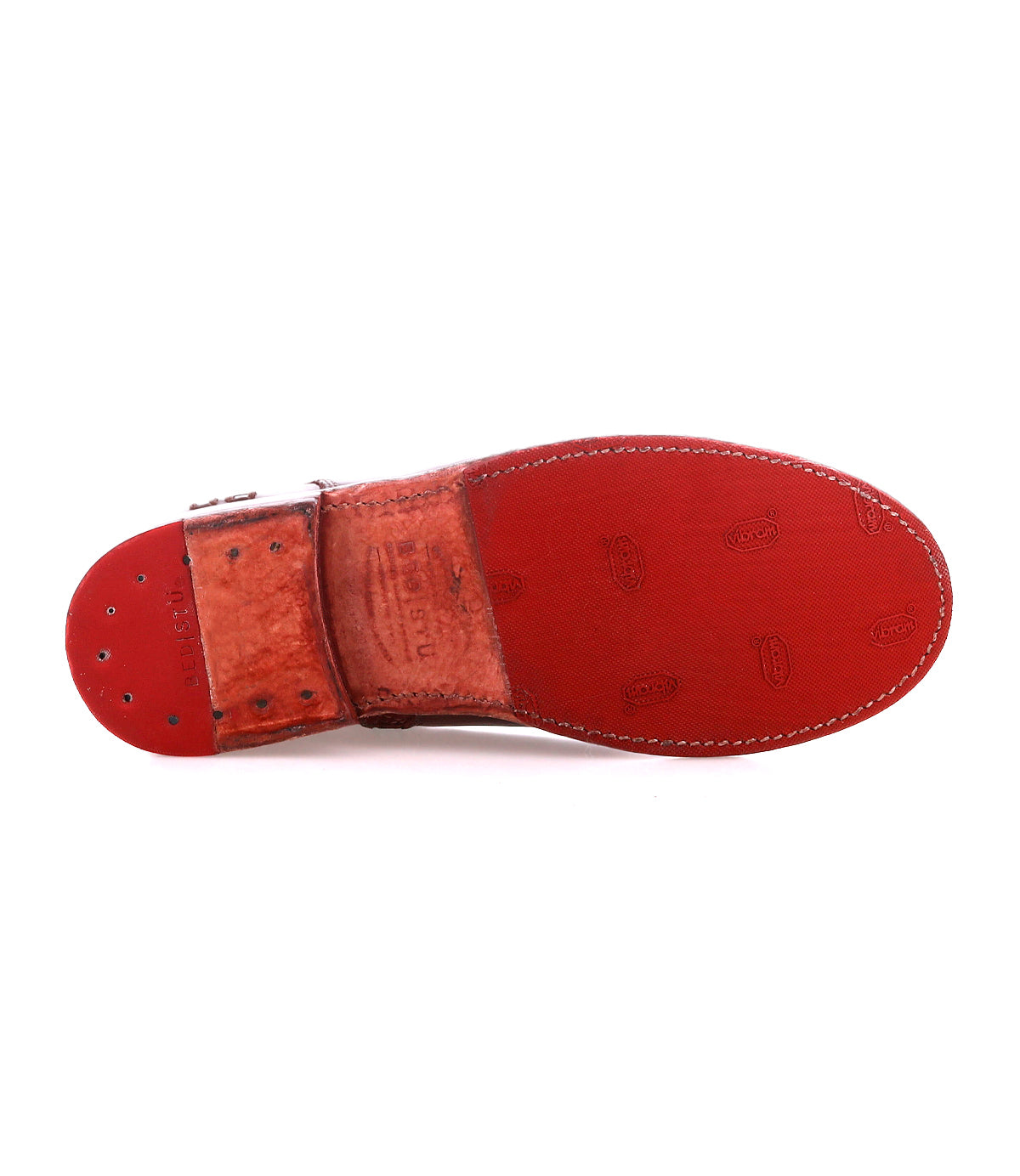 The image shows the Bed Stu Yurisa dress shoe, featuring a red sole with visible stitching and stamped logos, a brown leather heel section secured with metal rivets, and a glimpse of red leather lining inside.