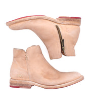 A pair of Bed Stu Yurisa tan leather ankle boots with side zippers, stacked heels, red soles, a rugged Vibram outsole, and visible stitching are shown against a white background.