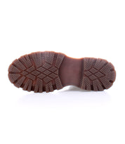 The image shows the sole of the Bed Stu Accelerate Chelsea boot, featuring a rugged lug outsole with a patterned tread design, displayed against a white background.