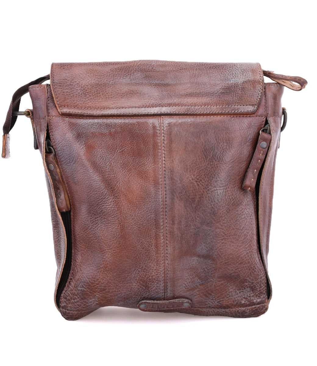 Brown leather crossbody handbag with a frontal flap, visible wear, and an adjustable strap, isolated on a white background by Bed Stu's Ainhoa LTC.