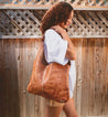 A woman wearing a tan leather Ariel hobo bag by Bed Stu.