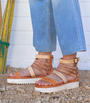 A woman in Bed Stu jeans and sandals standing next to a cactus.