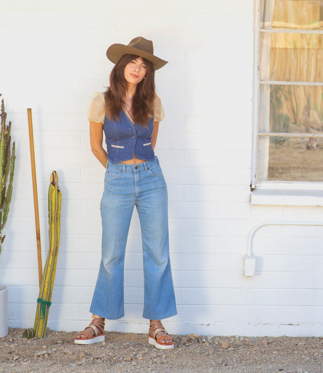 A woman wearing Bed Stu hat and jeans standing next to a cactus.