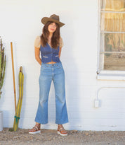 A woman wearing Bed Stu hat and jeans standing next to a cactus.
