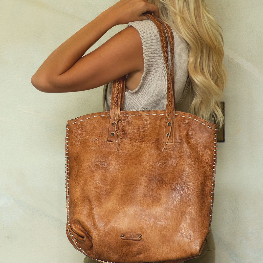 A blonde woman holding a Barra leather tote bag by Bed Stu.