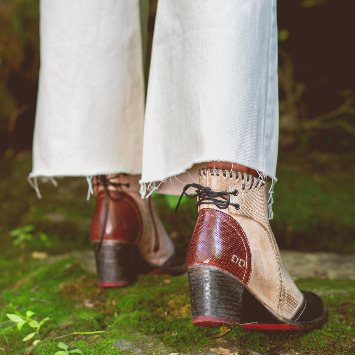 A woman's feet are wearing Bed Stu Bia sandals standing on a rock in the woods.