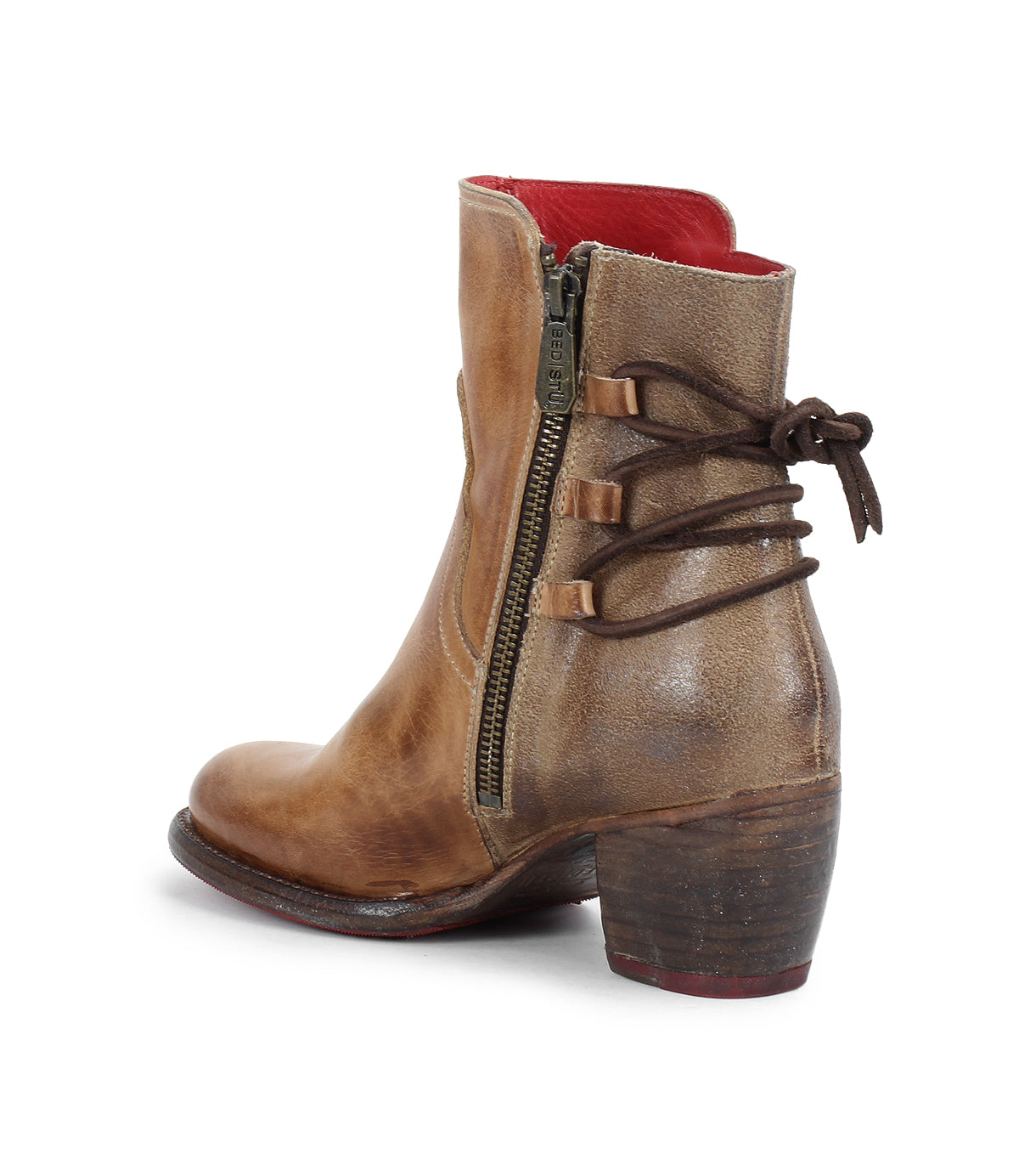 The Bed Stu Cable is a brown hand-finished leather mid-ankle boot with a low stacked heel, side zipper, decorative side ties, and a bold red interior lining—perfect for adding Western flair to your look.